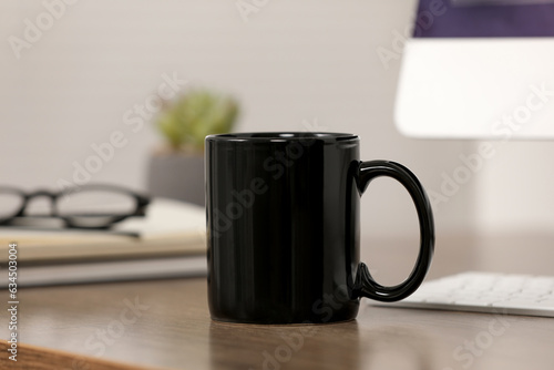 Black ceramic mug on wooden table at workplace