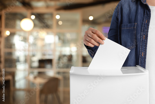 Fotografija Woman putting her vote into ballot box on blurred background, closeup