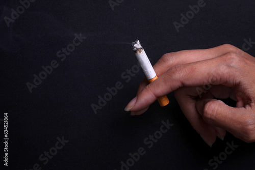 Closeup of hand holds lit cigarette on a dark background  © Queenmoonlite Studio