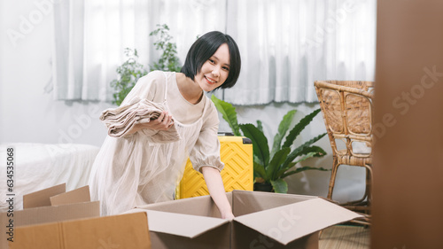 Woman unpack carton box in bedroom moving house to new home or apartment