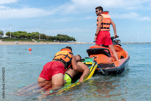 Lifeguards rescue a man in the sea using a jet ski photo