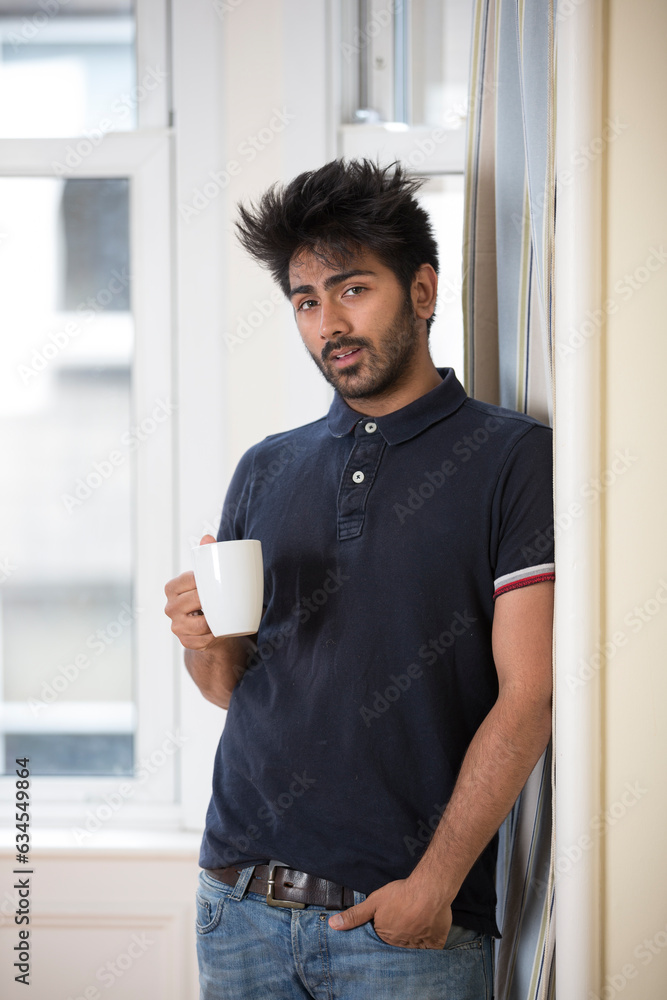 Indian man at home with a mug of hot drink. Indian man at home with a mug of hot drink.