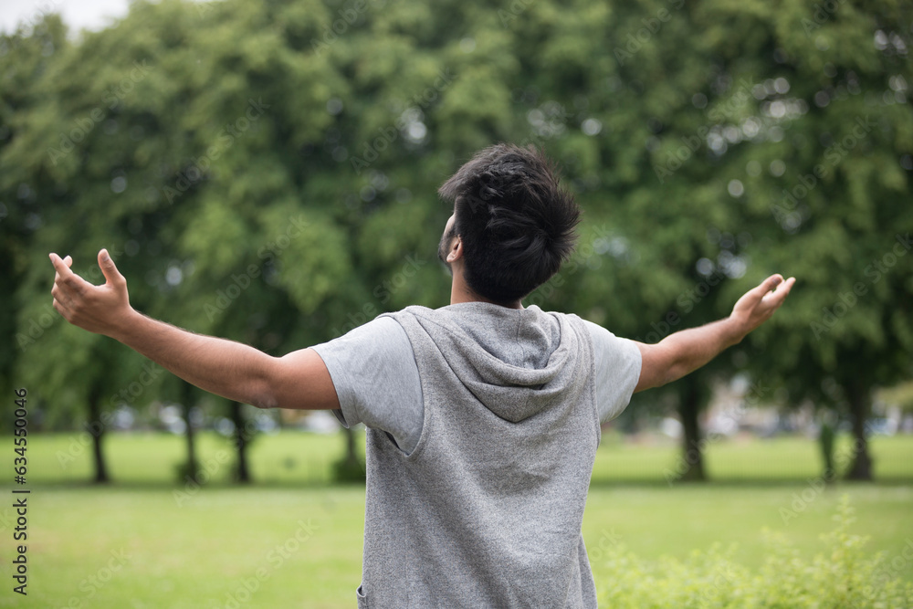 Asian man standing with arms raised outdoors. Asian man standing with arms raised outdoors.