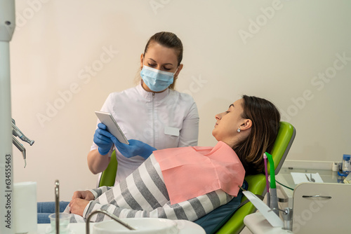 Female dentist doctor during consultation showing patient tablet