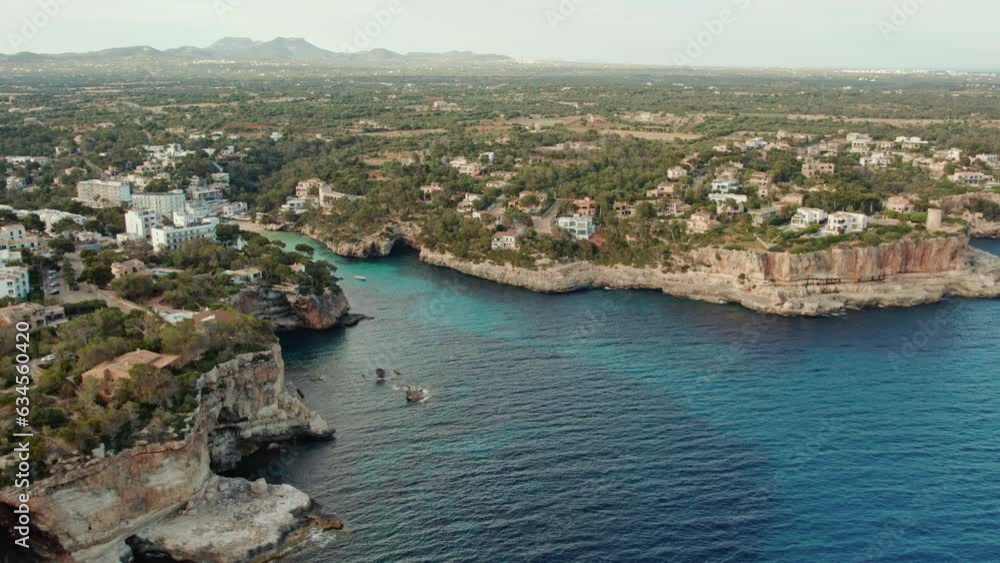 Coastal Town Surrounded By Forest And Stone Cliffs In Playa de Santanyi, Cala Santanyi, Balearic Islands, Mallorca, Spain. Aerial Drone Coastal Town Surrounded By Forest And Stone Cliffs In Playa de Santanyi, Cala Santanyi, Balearic Islands, Mallorca, Spain. Aerial Drone