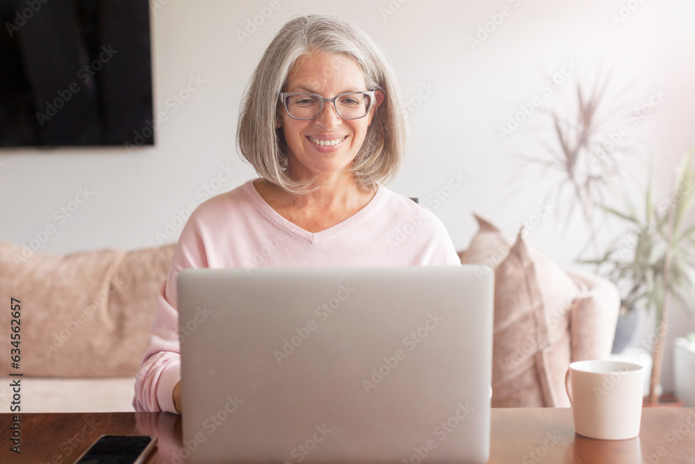 Happy stylish mature old woman remote working from home distance office on laptop