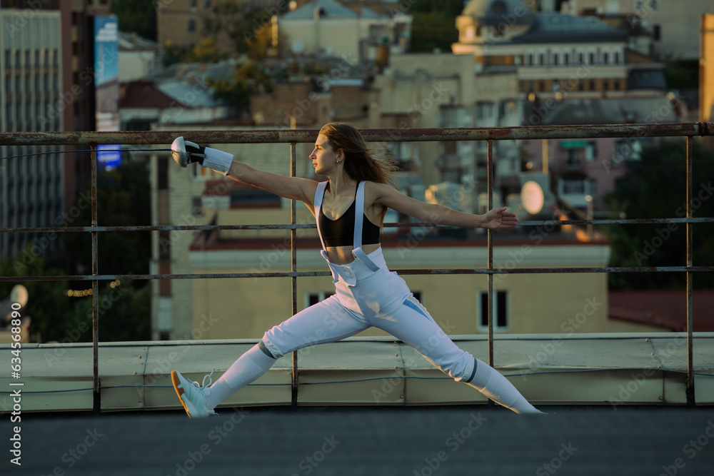 Two fencers woman practice on a rooftop with the city in the background. Two fencers woman practice on a rooftop with the city in the background.