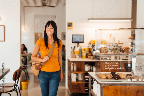 Happy woman walking with shoulder bag in cafe