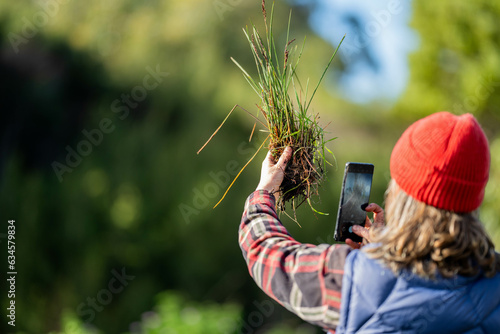 Photography regenerative organic female farmer, taking soil samples and looking at plant growth in a farm