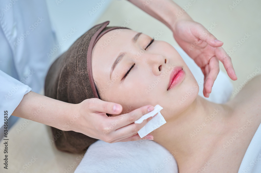 아시아 한국의 젊은 한국여성 모델은 거즈를 이용해 스파 또는 피부관리전문점 또는 피부과 병원의 침대에 누워서 전문관리사에게 머리와 얼굴을 관리를 받음