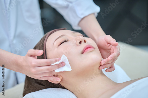 아시아 한국의 젊은 한국여성 모델은 거즈를 이용해 스파 또는 피부관리전문점 또는 피부과 병원의 침대에 누워서 전문관리사에게 머리와 얼굴을 관리를 받음