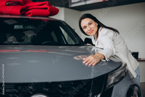 Woman hugging a new car in a car showroom