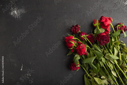 Withered, decaying, roses flowers on black concrete background. top view, copy space.