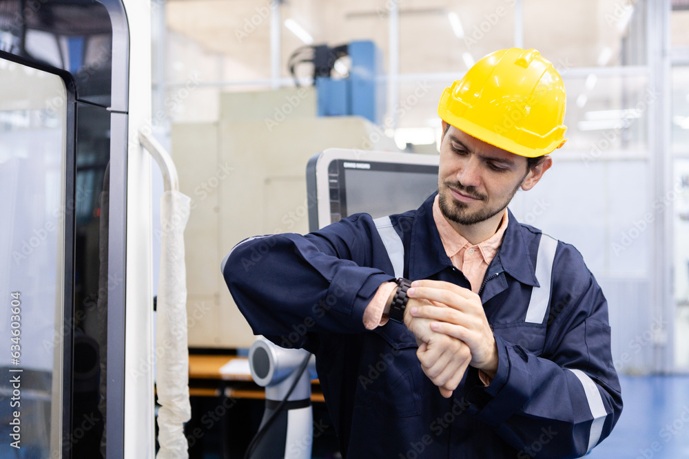 Man engineer looking watch time off work at workshop. professional male control automated machine process programming cnc machine at industry manufacturing. Man engineer looking watch time off work at workshop. professional male control automated machine process programming cnc machine at industry manufacturing.