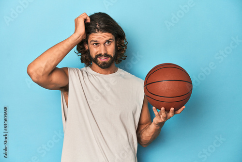 Bearded man with basketball in blue studio being shocked, she has remembered important meeting.