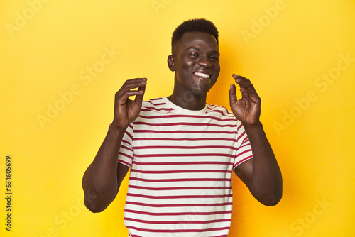Stylish young African man on vibrant yellow studio background, joyful laughing a lot. Happiness concept.