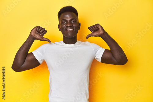 Stylish young African man on vibrant yellow studio background, feels proud and self confident, example to follow.