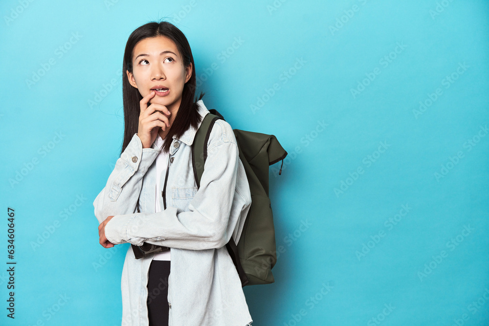 Young Asian traveler ready to capture adventures, relaxed thinking about something looking at a copy space. Young Asian traveler ready to capture adventures, relaxed thinking about something looking at a copy space.