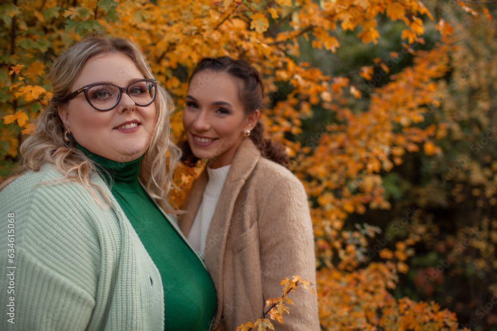 Fototapeta premium Multiracial female people with different bodies and hairs walking in the fall parks together. Friends wearing warm fashion clothes, knitted sweaters.