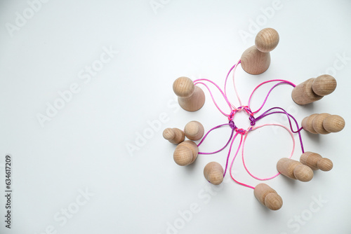 A round knot of threads unites wooden figures. Place for text