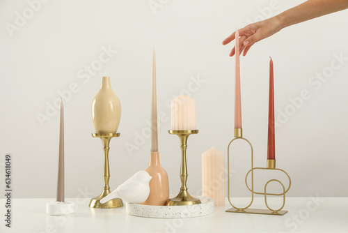 Candles on holders and female hand on white background