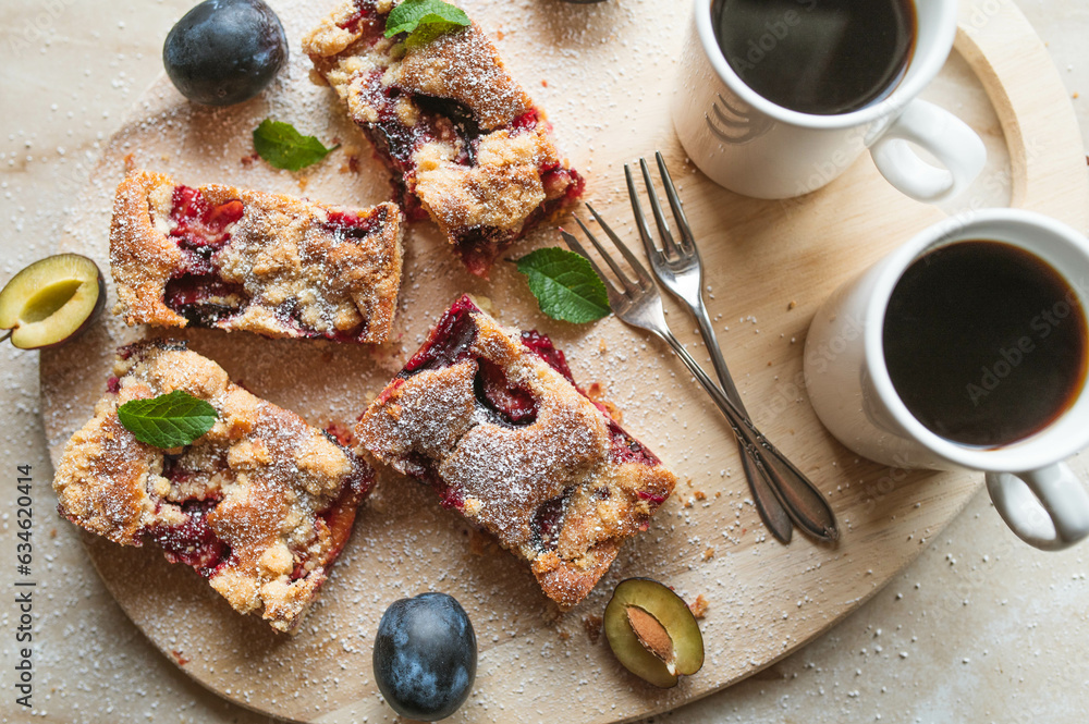 Slab pie with plums and crumbles on a wooden platter with coffee