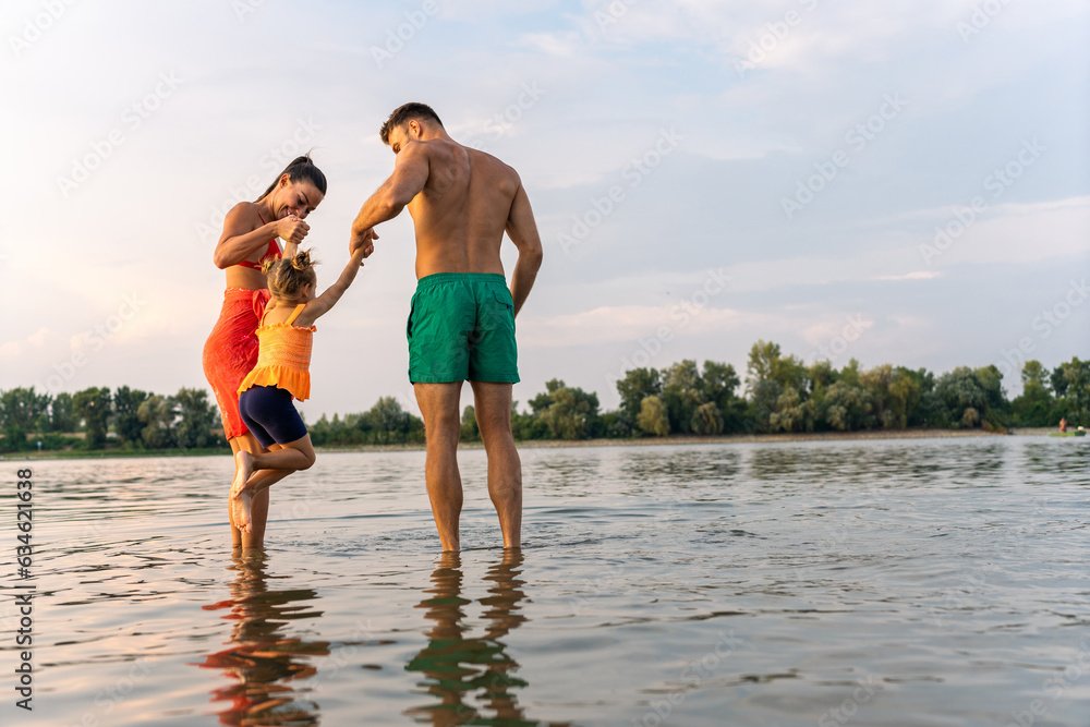 portrait of happy family playing with cute little girl while enjoying walk on beach during Summer vacation portrait of happy family playing with cute little girl while enjoying walk on beach during Summer vacation