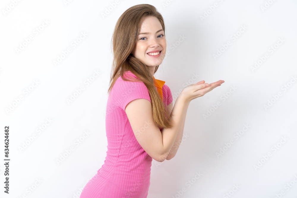 Young woman wearing pink dress pointing aside with hands open palms showing copy space, presenting advertisement smiling excited happy Young woman wearing pink dress pointing aside with hands open palms showing copy space, presenting advertisement smiling excited happy
