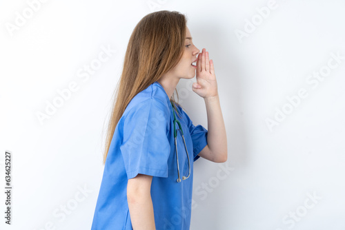 Half-faced close up portrait of astonished amazed Young caucasian doctor woman wearing medical uniform holding hand near mouth photo