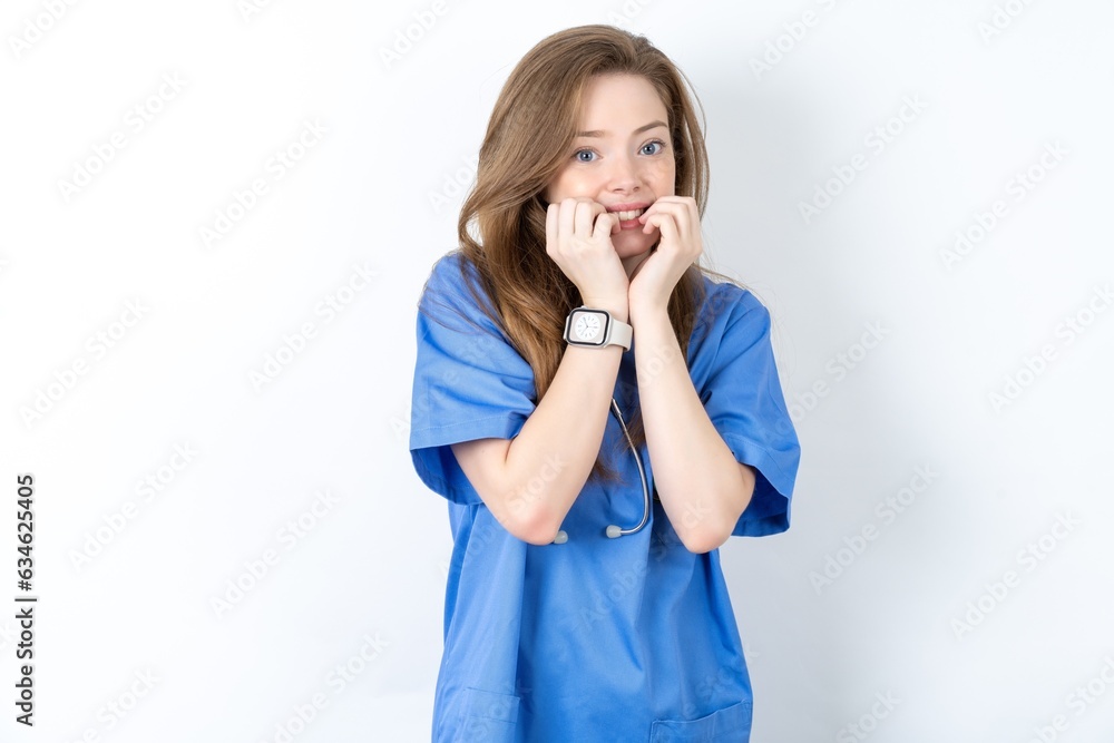Fearful Young caucasian doctor woman wearing medical uniform keeps hands near mouth, feels frightened and scared, has a phobia, Shock and frighted concept. Fearful Young caucasian doctor woman wearing medical uniform keeps hands near mouth, feels frightened and scared, has a phobia, Shock and frighted concept.