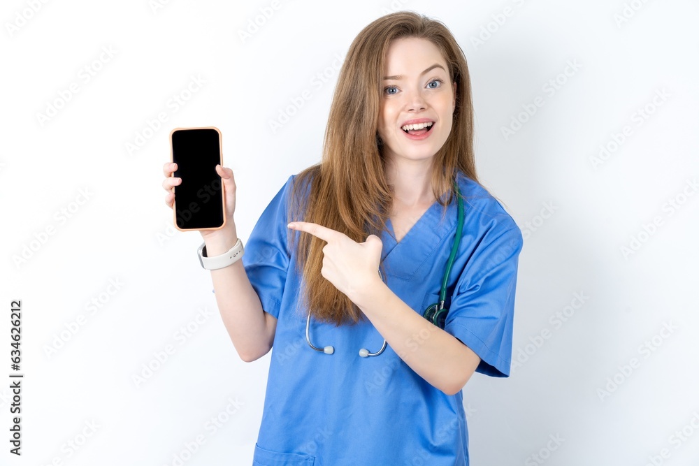Attractive cheerful Young caucasian doctor woman wearing medical uniform holding in hands cell showing black screen Attractive cheerful Young caucasian doctor woman wearing medical uniform holding in hands cell showing black screen