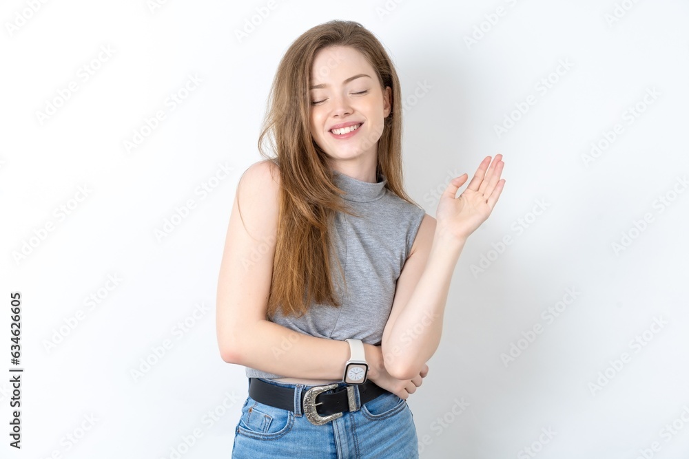Overjoyed successful Young beautiful girl wearing grey T-shirt raises palm and closes eyes in joy being entertained by friends Overjoyed successful Young beautiful girl wearing grey T-shirt raises palm and closes eyes in joy being entertained by friends