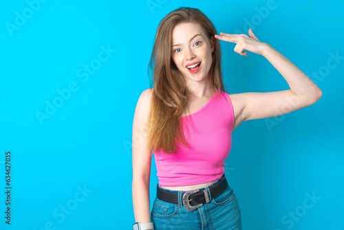 Canvas Print Young beautiful girl wearing pink T-shirt foolishness around shoots in temple with fingers makes suicide gesture