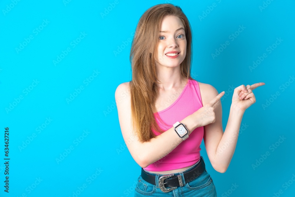 Young beautiful girl wearing pink T-shirt points at copy space indicates for advertising gives right direction Young beautiful girl wearing pink T-shirt points at copy space indicates for advertising gives right direction