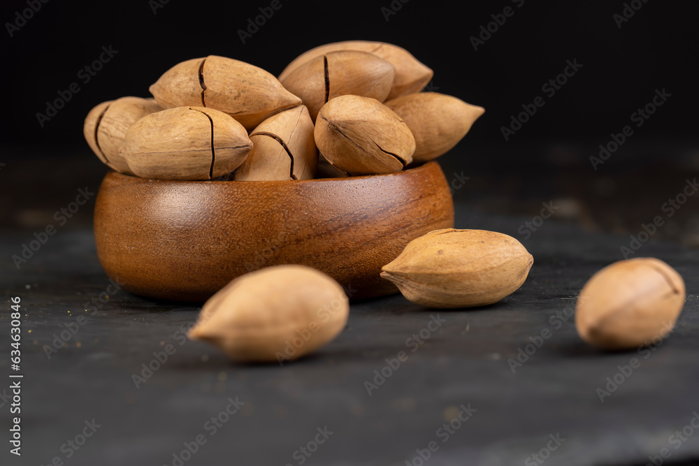 Obraz premium unpeeled pecans in a shell on the kitchen table, close up