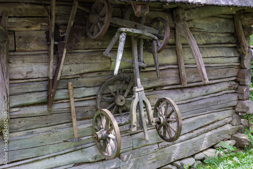Old partly broken rural wagon undercarriage hangs on wooden wall