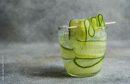 Glass of cucumber water or a cucumber cocktail on a table photo