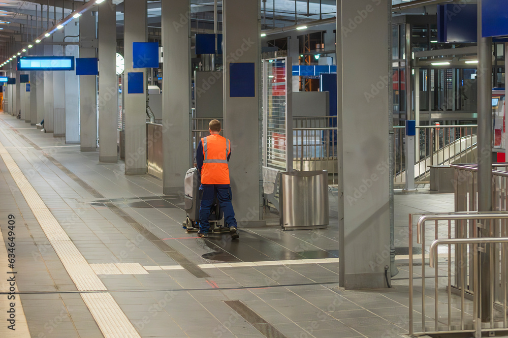 Arbeiter säubert den Boden mit einer Scheuersaugmaschine