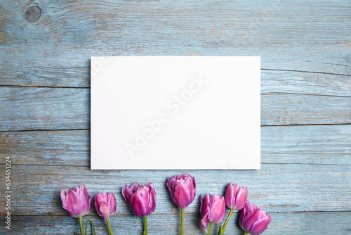 Blank white canvas mockup with flowers on a blue wood background. Blank canvas print on vintage wall