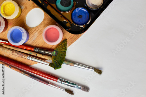 Flat lay of colorful paints, painting palette and brushes