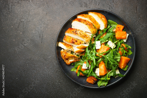 Warm salad with baked chicken breast, pumpkin, blue cheese and arugula. Dash diet, keto diet meal. Top view image.
