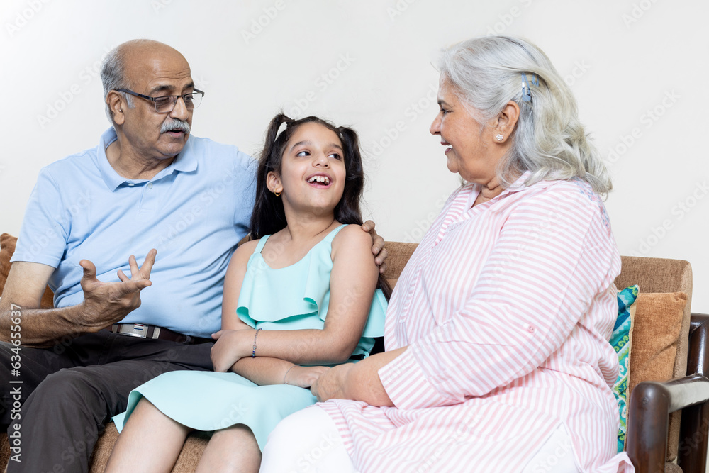 Grandparents and grand daughter having conversation together and looking each other ,