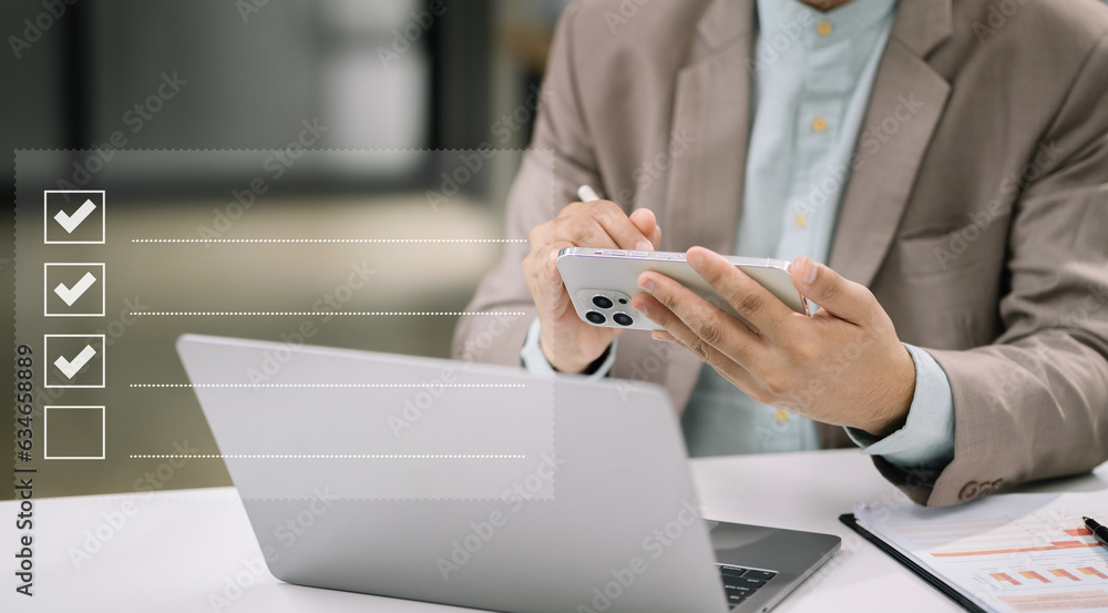 Fototapeta premium Businessman using smartphone to do online checklist survey, doing assessment online survey answer test questions Digital form.