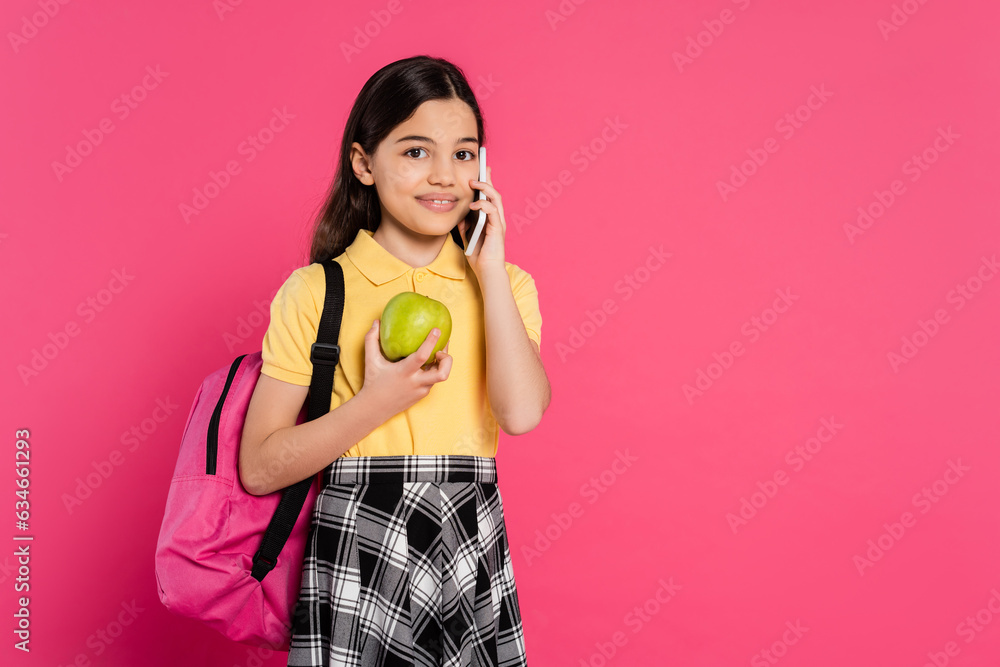 happy schoolgirl standing with backpack, holding apple and talking on smartphone, phone call happy schoolgirl standing with backpack, holding apple and talking on smartphone, phone call