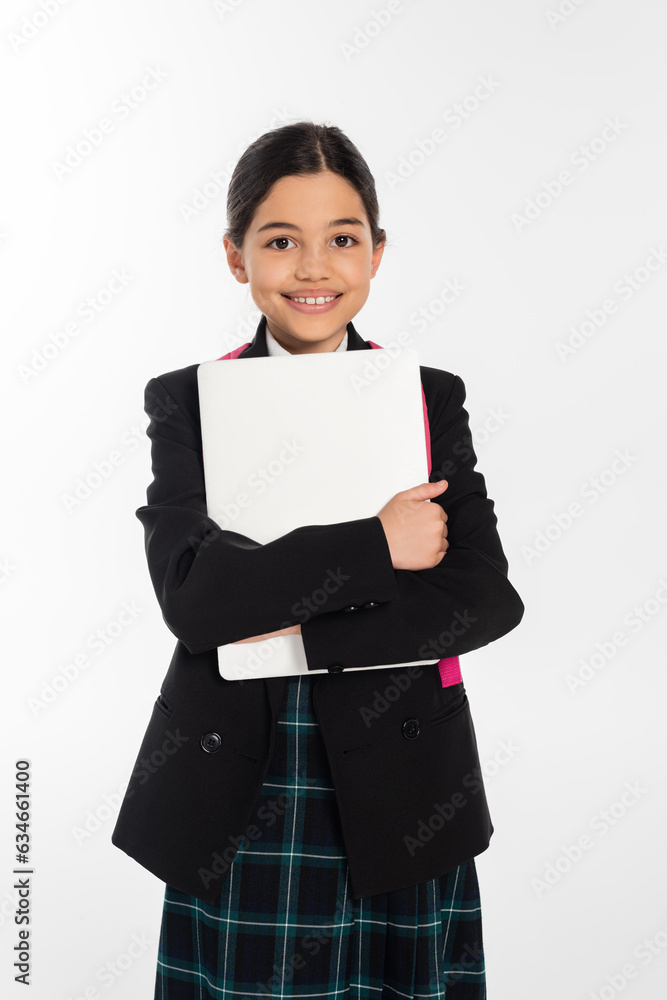 joyful schoolgirl holding laptop and looking at camera, girl in school uniform, isolated on white joyful schoolgirl holding laptop and looking at camera, girl in school uniform, isolated on white