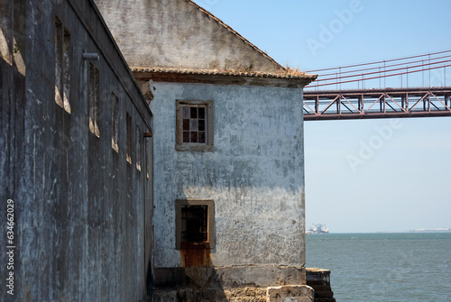The "Ponte 25 de Abril" bridge in Lisbon, Portugal, with an abandoned building in the foreground