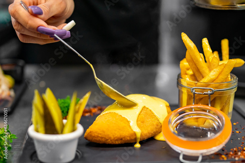 chef cooking Fried Wiener schnitzel with French fries and cheese sauce on kitchen