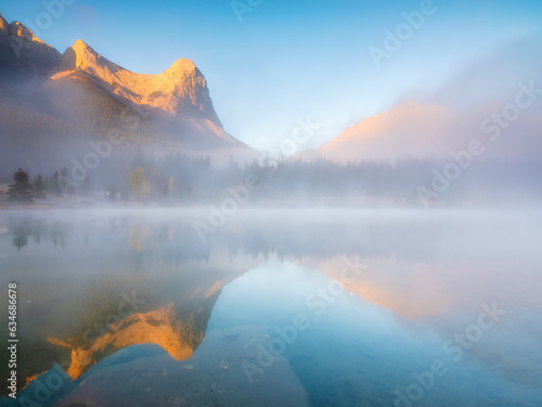 Fall. Landscape during sunrise. Foggy weather. Autumn trees on the river bank. Mountains and forest. Reflections on the surface of the lake. Banff National Park  Alberta  Canada.