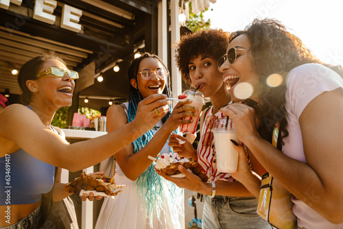 Group of african women eating takeaway street food in park