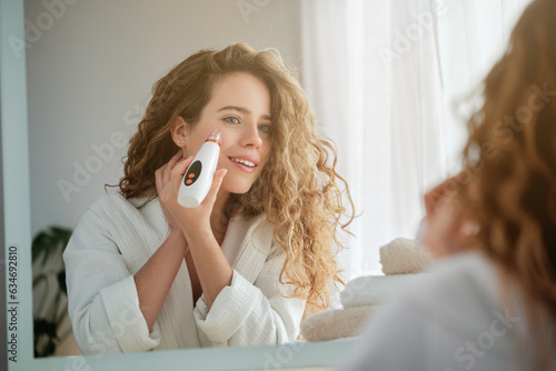 Tableau sur toile Woman using electric acne remover